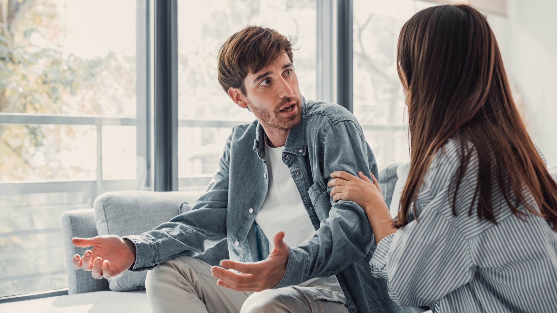 Man looking defensive talking to his partner on a couch