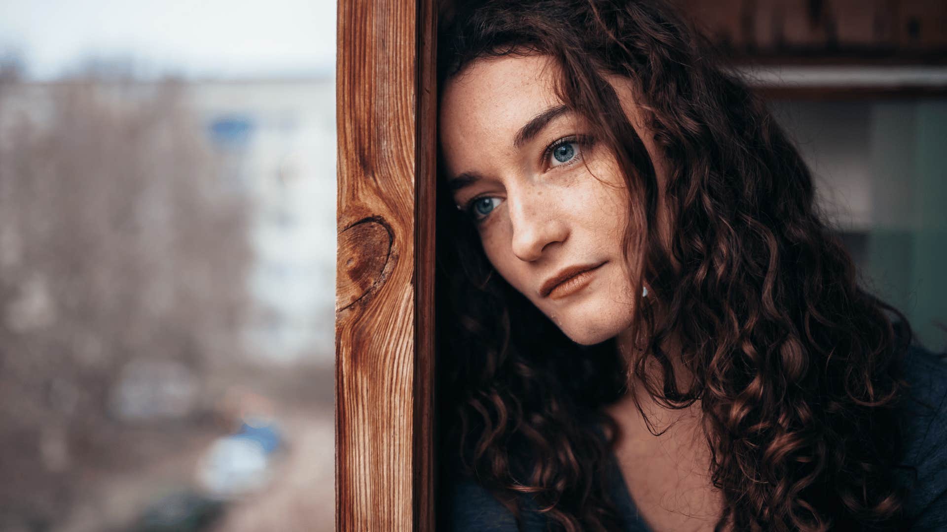 sad woman leaning on window