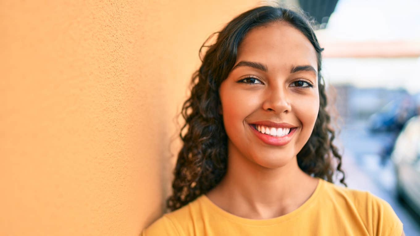 smiling happy resilient woman leaning on building