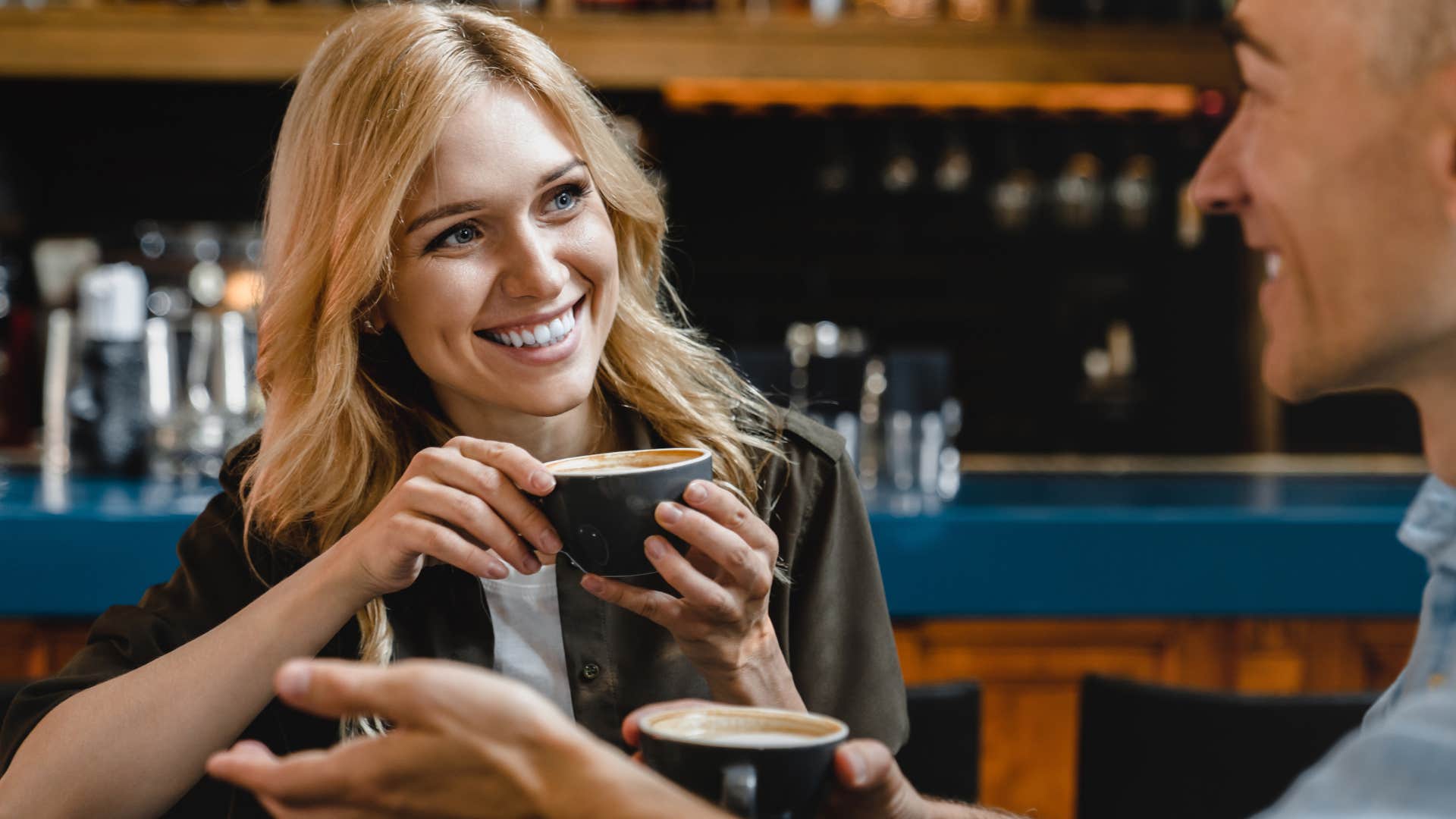 Woman smiling and drinking coffee with a man