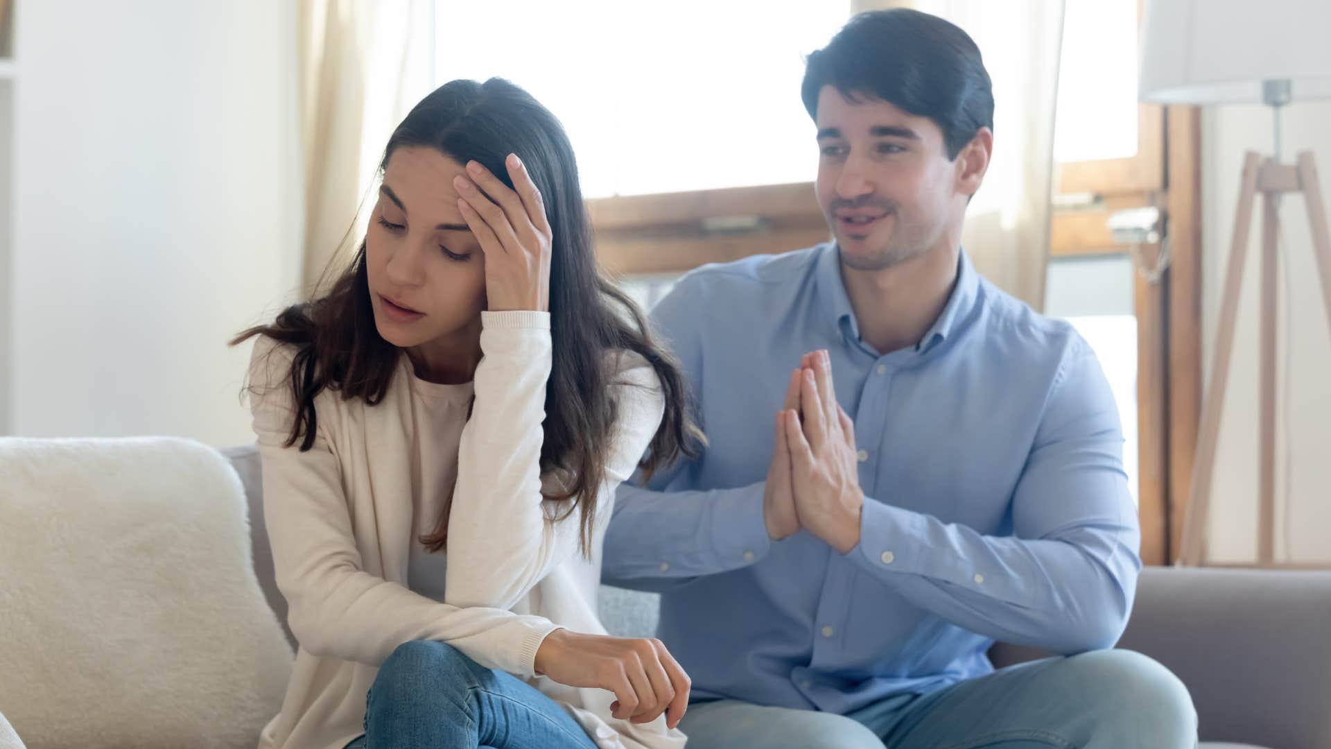 Man pleading with his upset wife on a couch