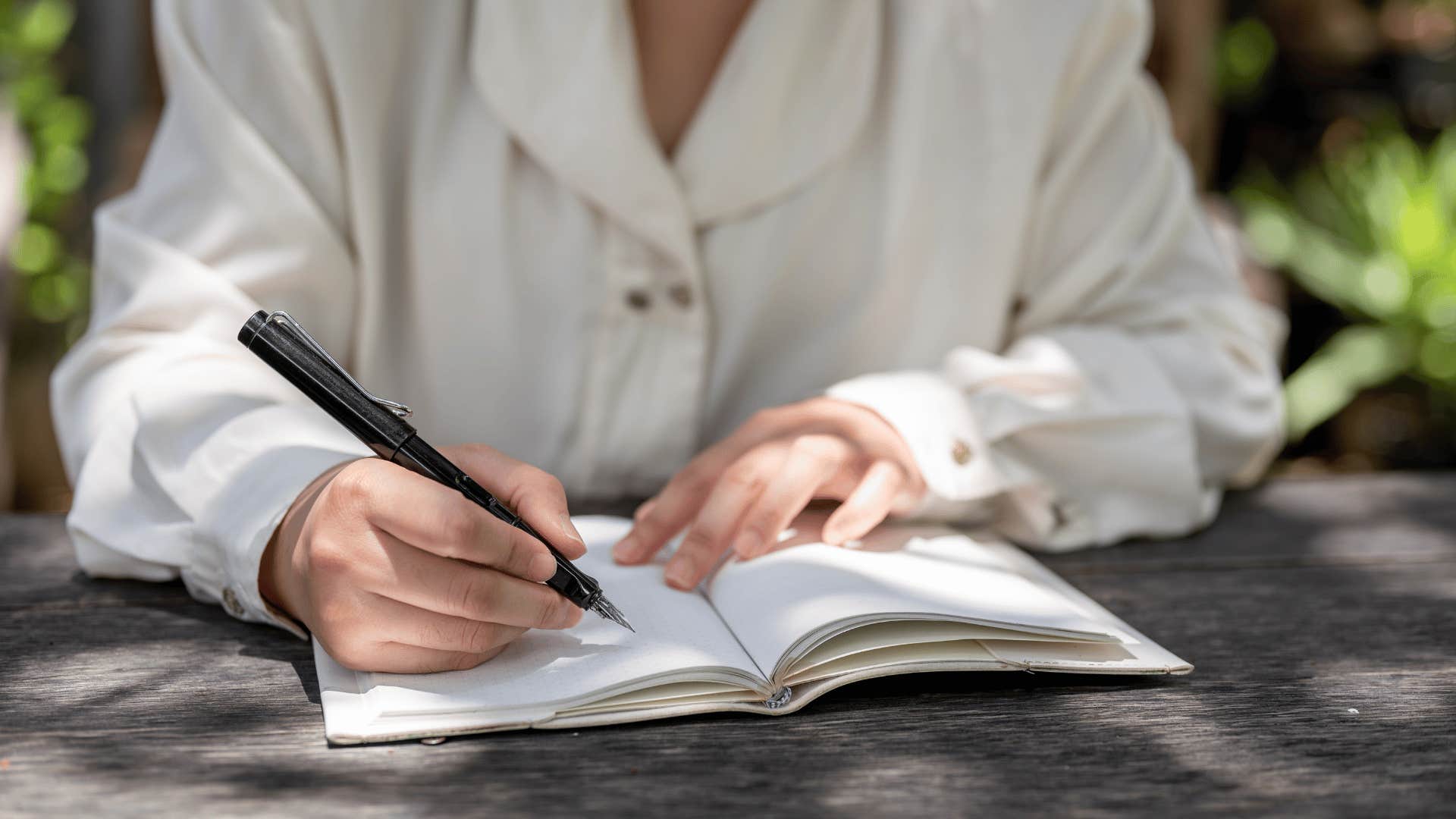 person writing in a journal outside