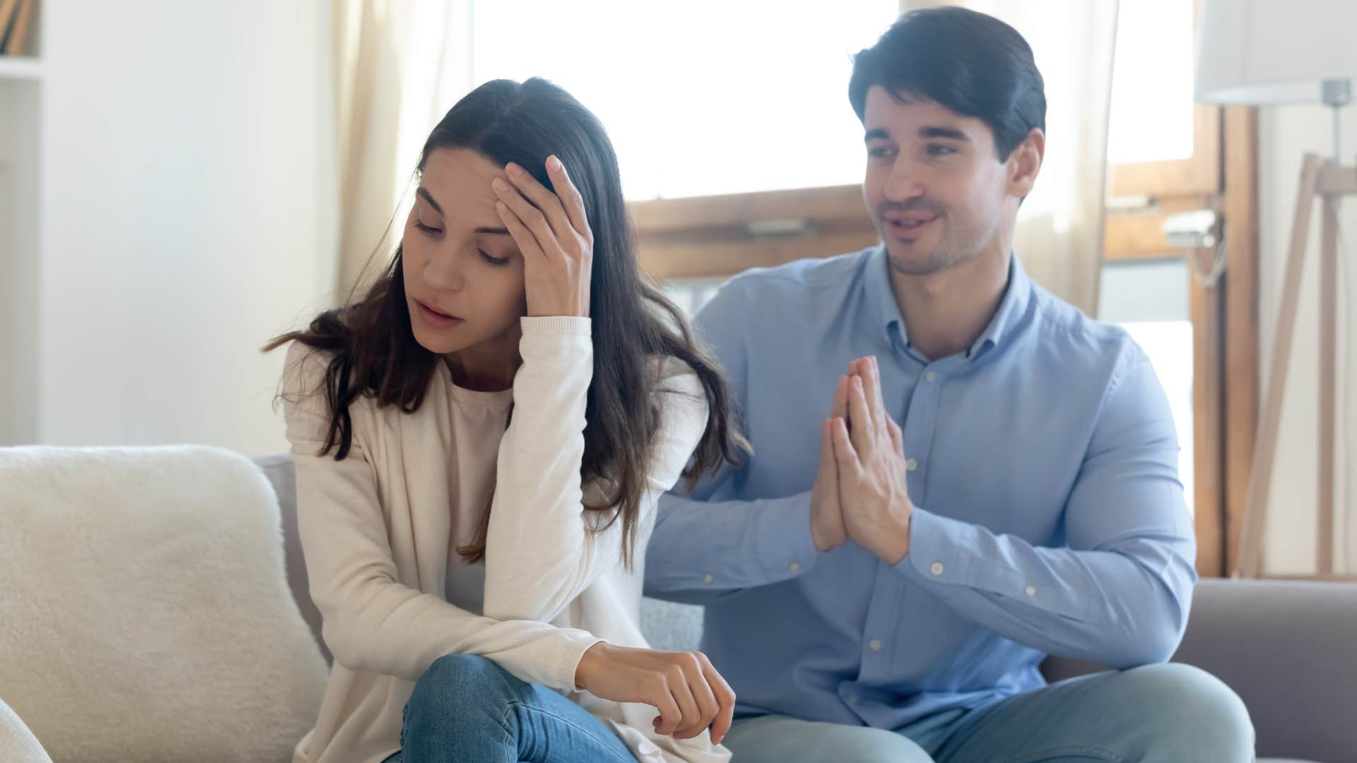 Man pleading with his upset wife on a couch.