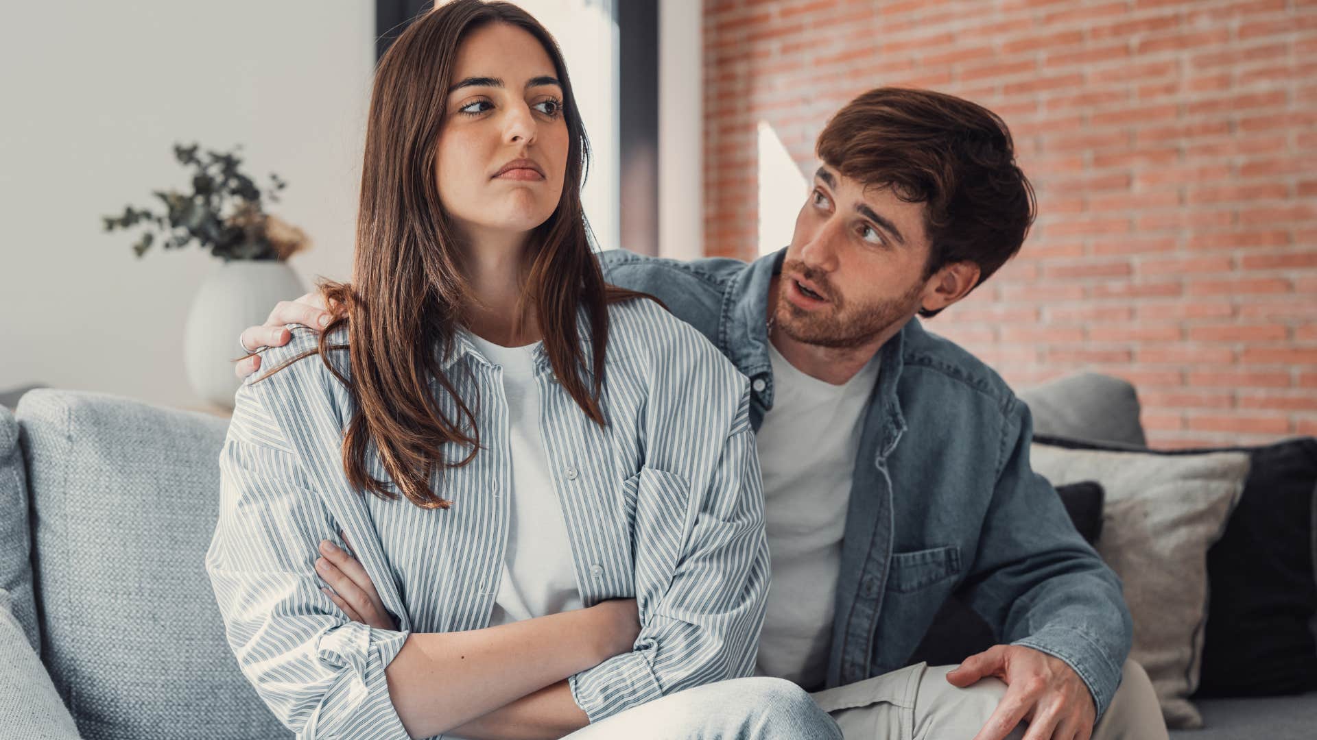 Man comforting his angry wife on the couch.