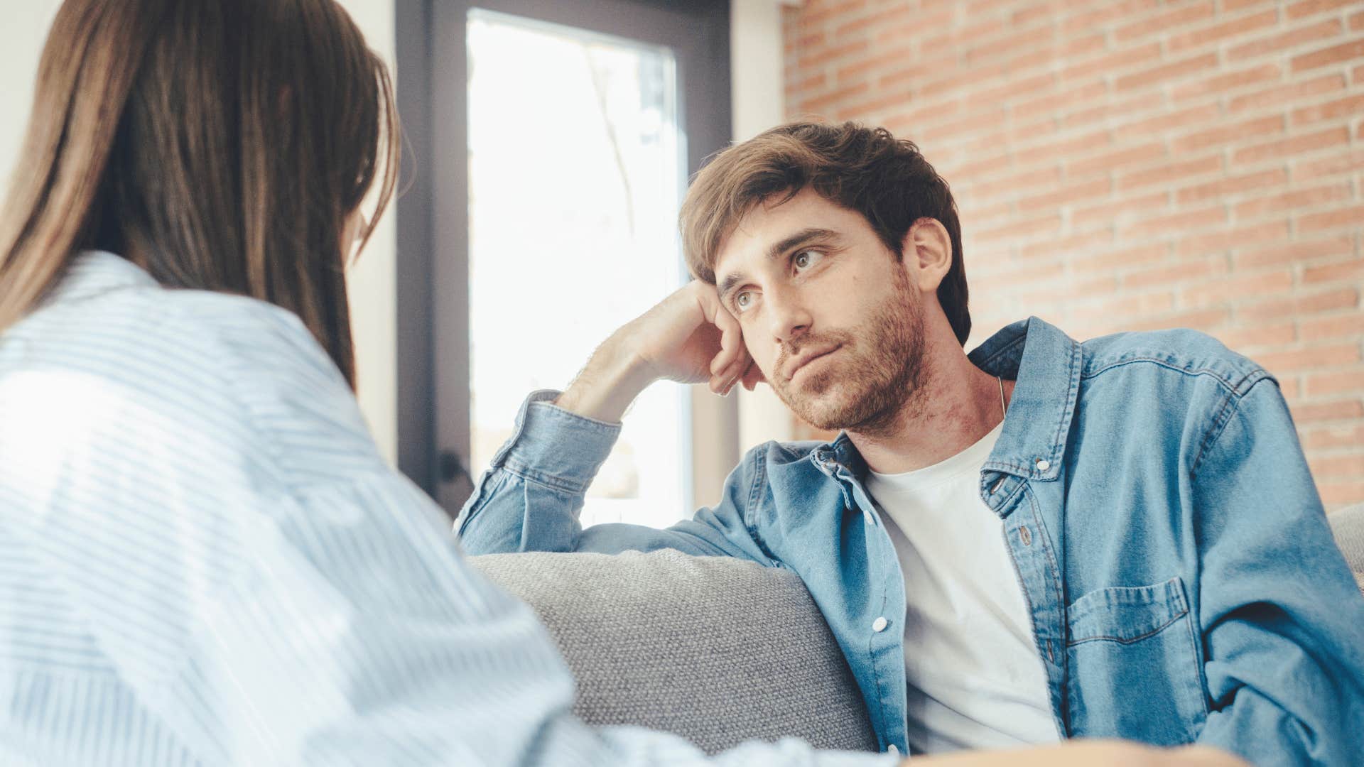 man and woman talking on couch