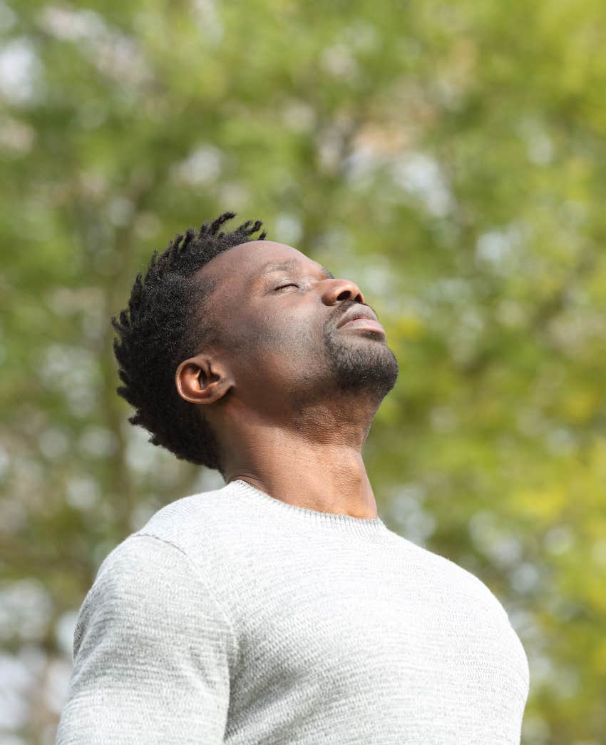 Mindful man in a park closes his eyes to reflect on broken heart