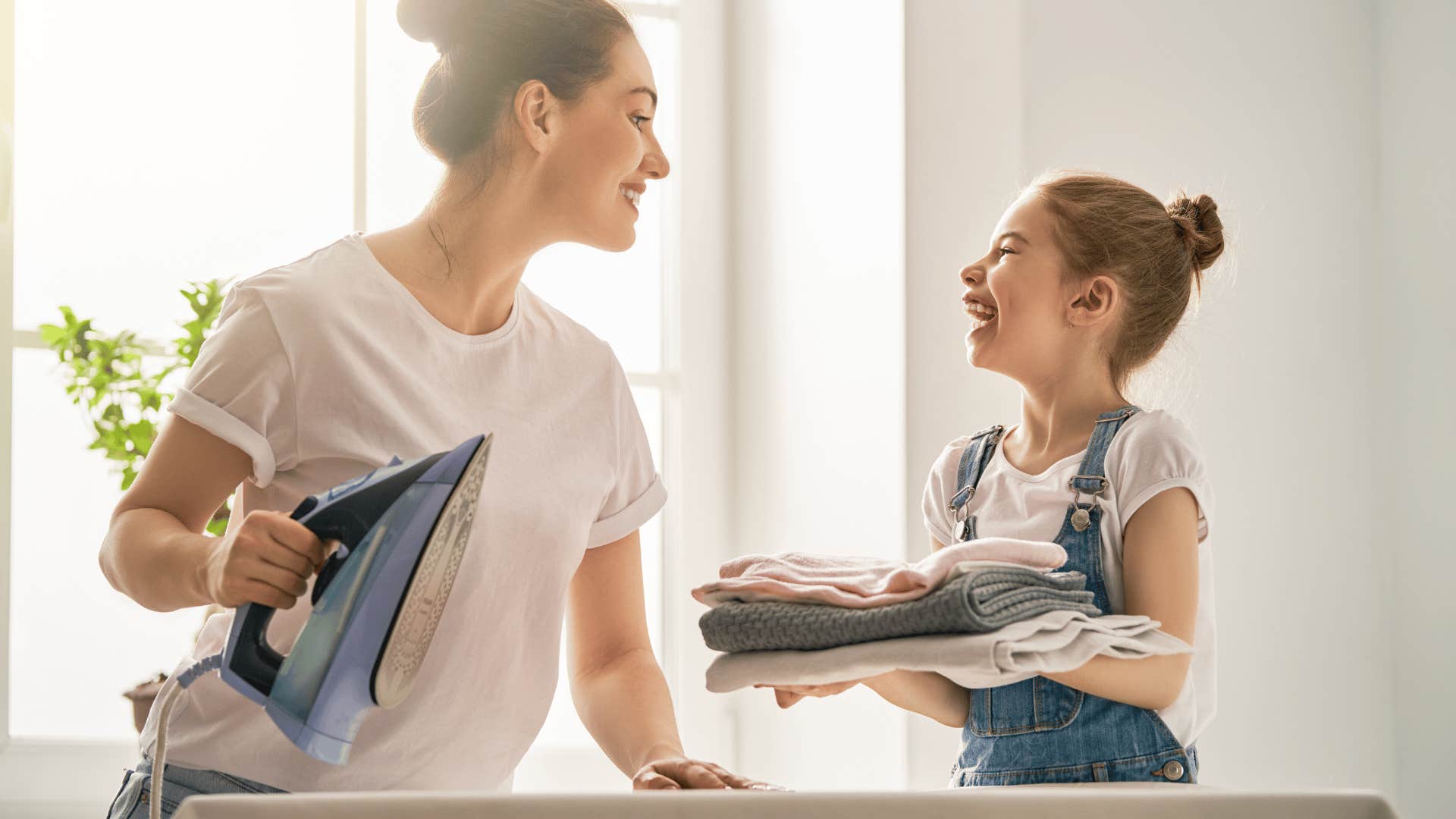 Mom and daughter have fun ironing clothes