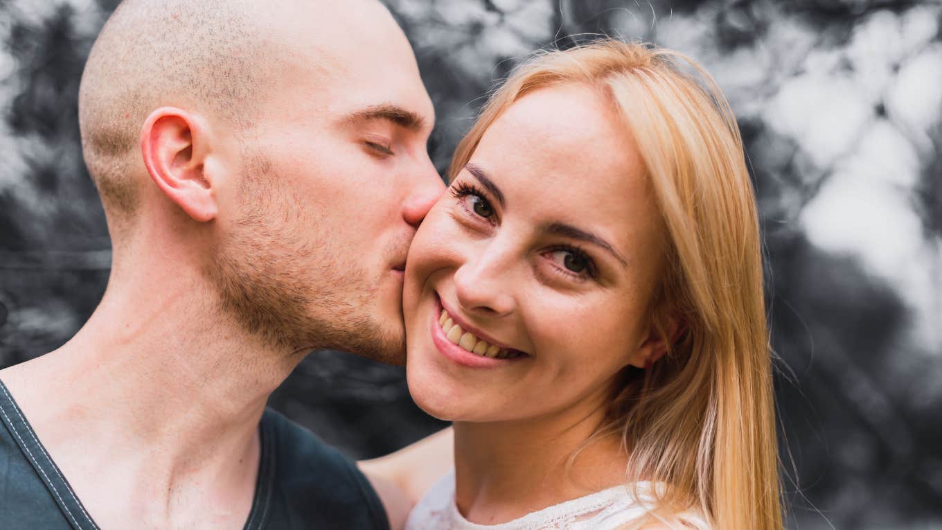  Young couple kisses on the cheek.