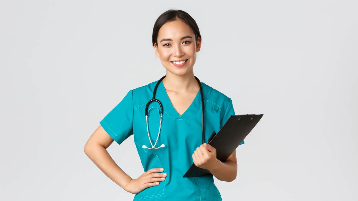 smiling nurse wearing scrubs and holding a clipboard