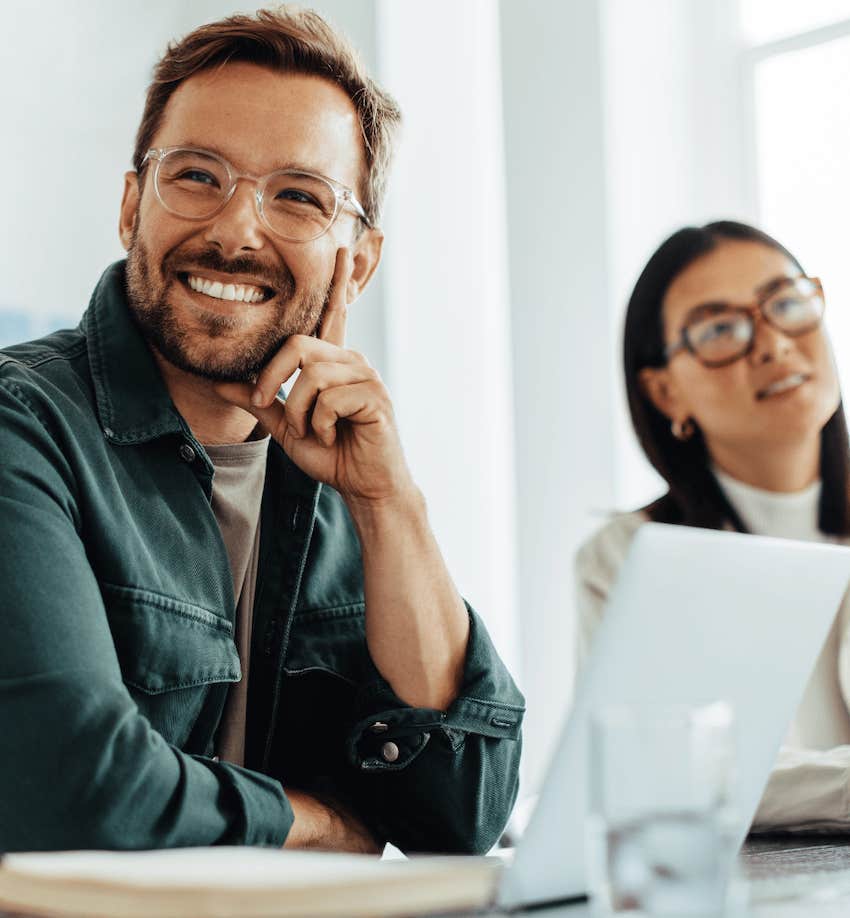 Man and woman in office smile and listen attentively