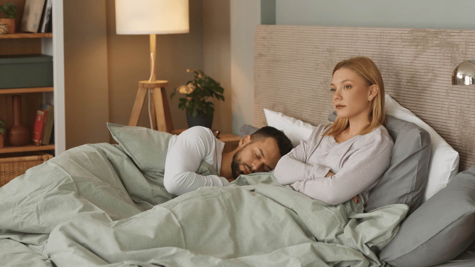 woman lying up in bed next to man