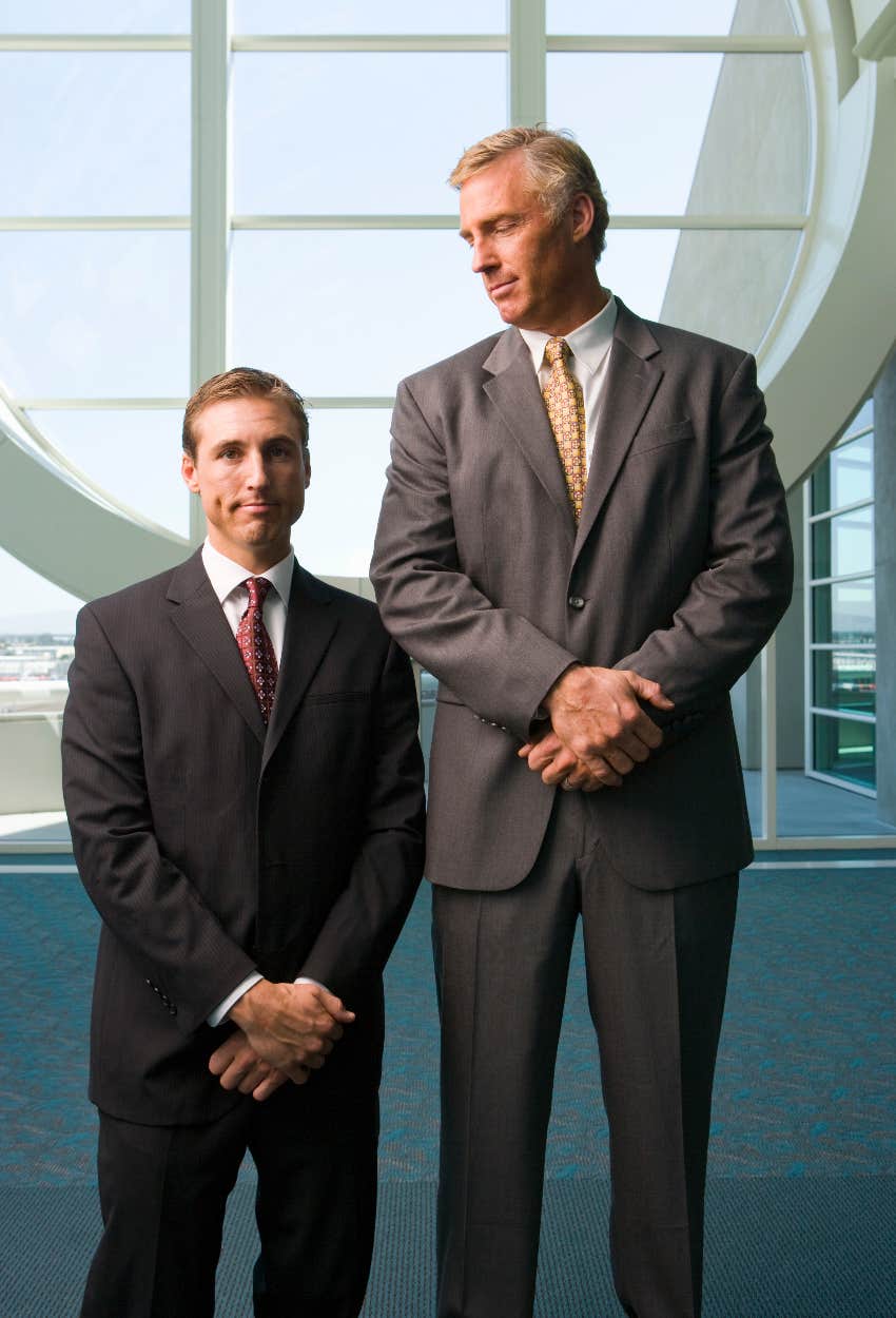 Short man standing next to a much taller man