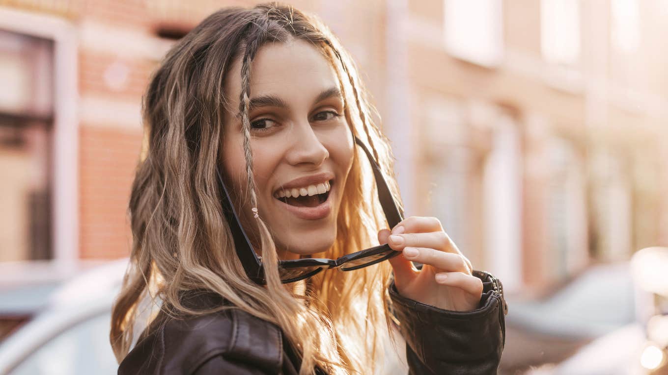 Extremely creative woman with braids and wavy hair smiles at camera