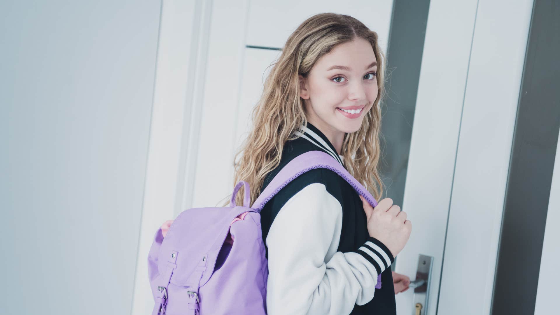 teen girl about to walk out door wearing backpack