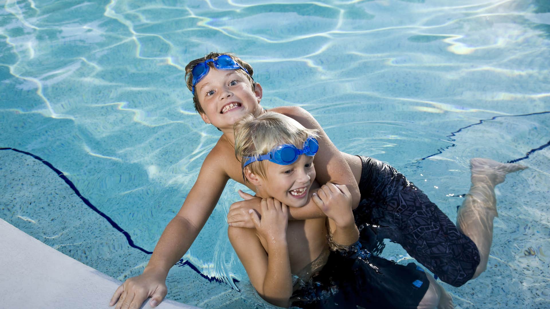 two boys engaged in rough play while swimming