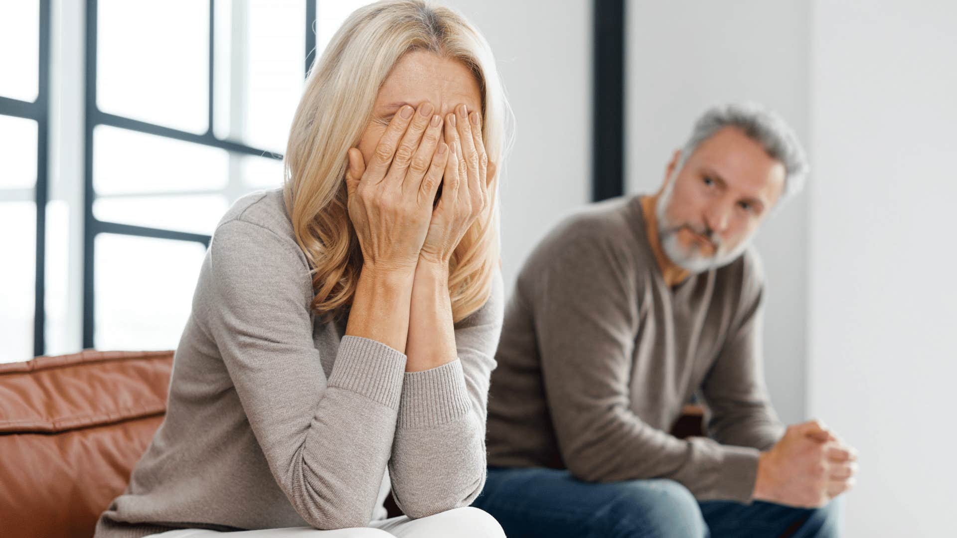 woman crying into her hands next to man