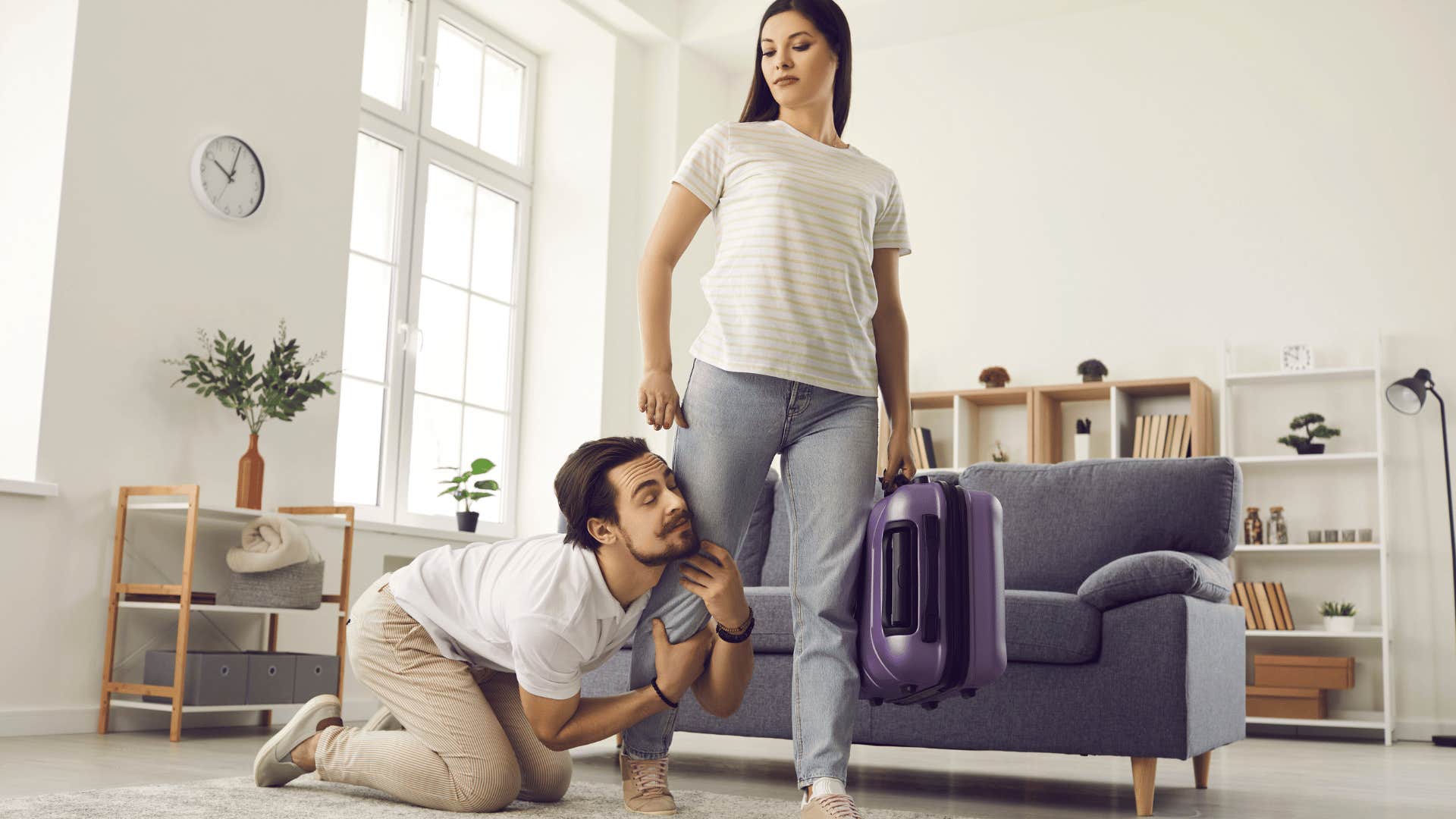 man clinging to woman's leg as she tries to leave