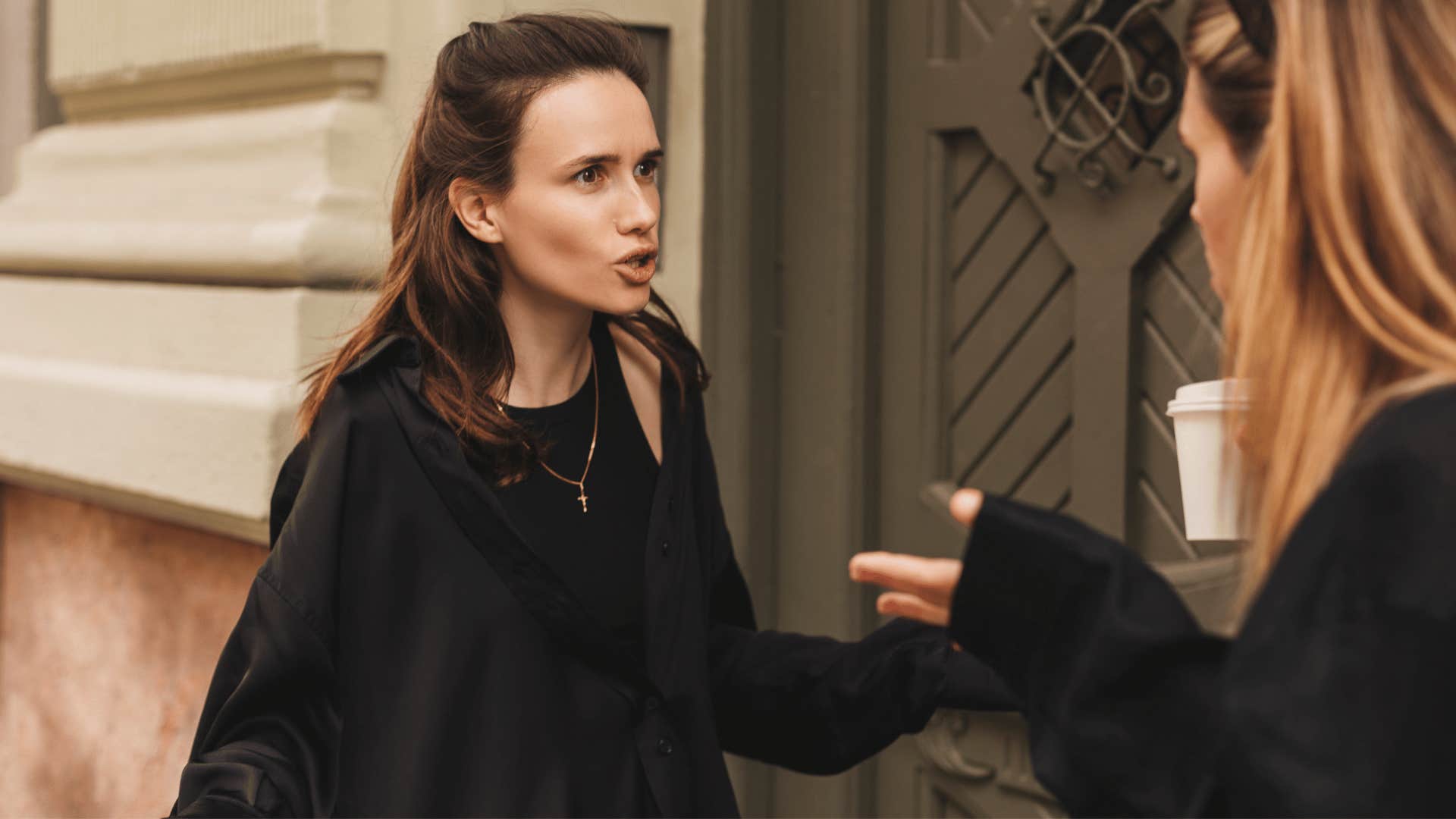 two women arguing outside of building