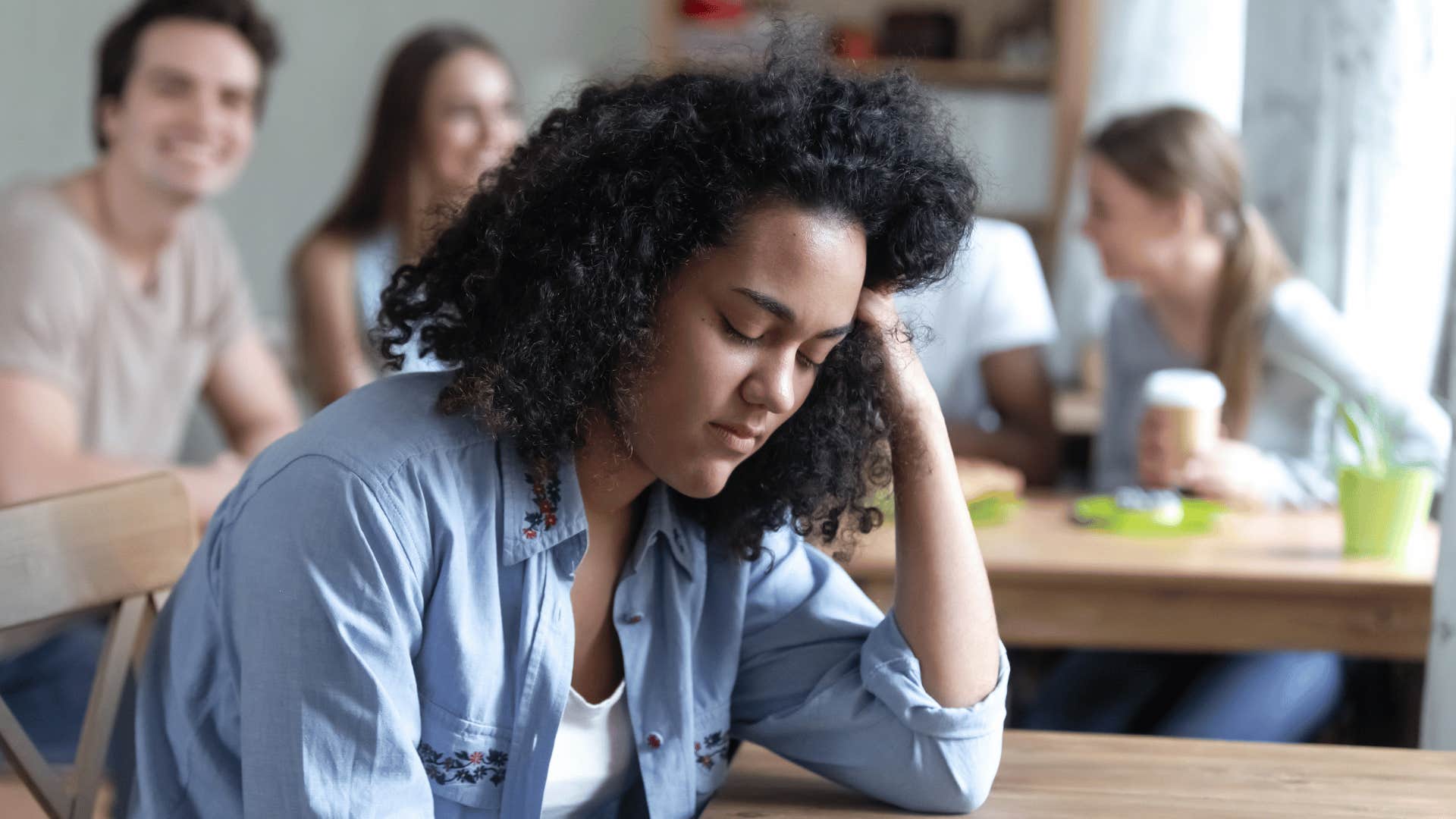 woman looking upset while being isolated from friends