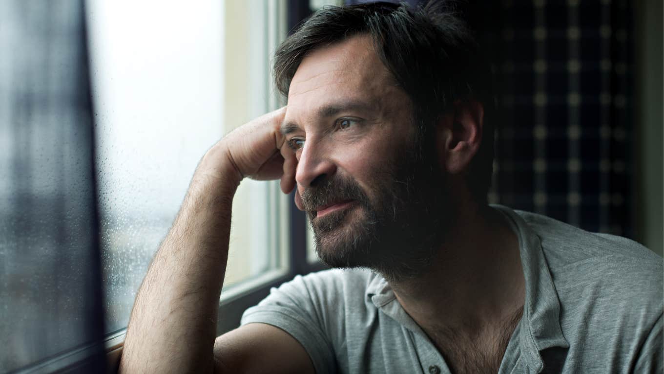 man looking out rainy window