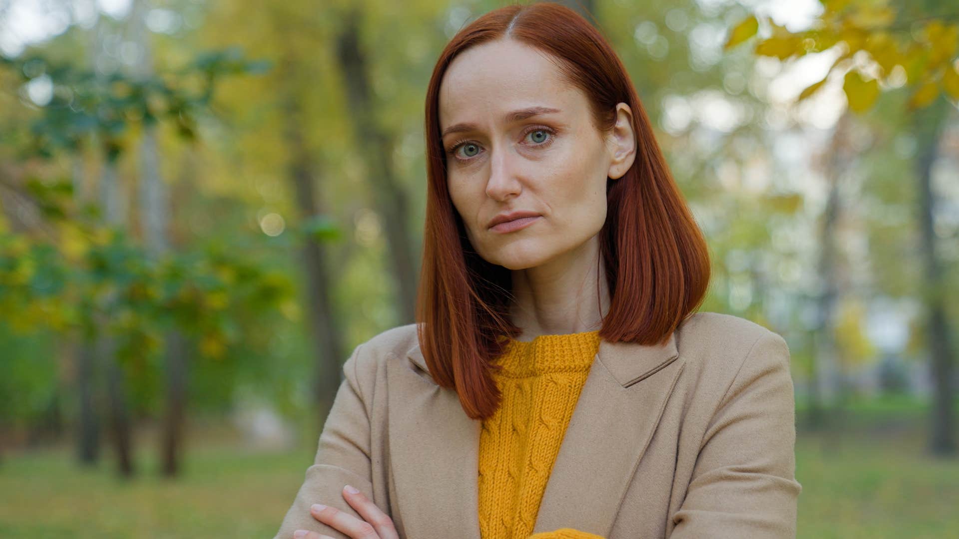 Woman crossing her arms and looking upset outside.