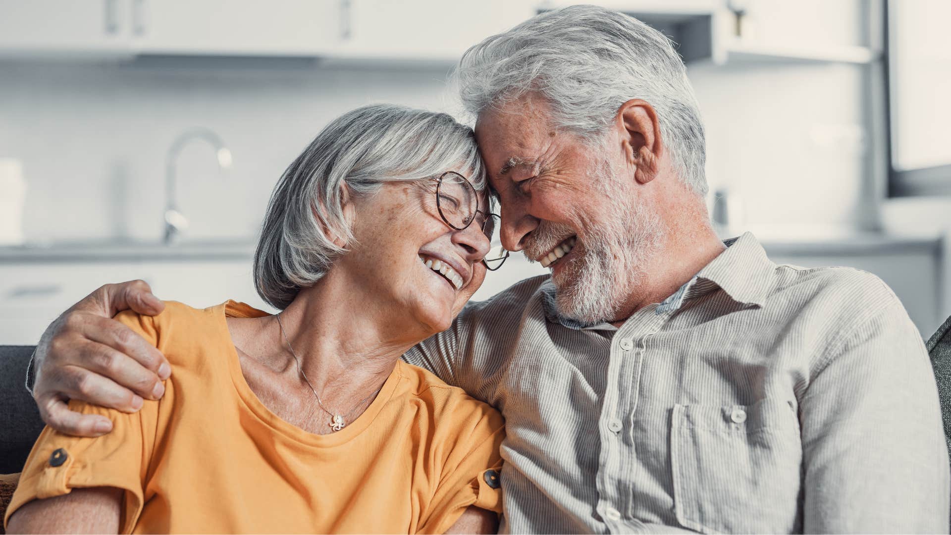 Older couple smiling and hugging each other.