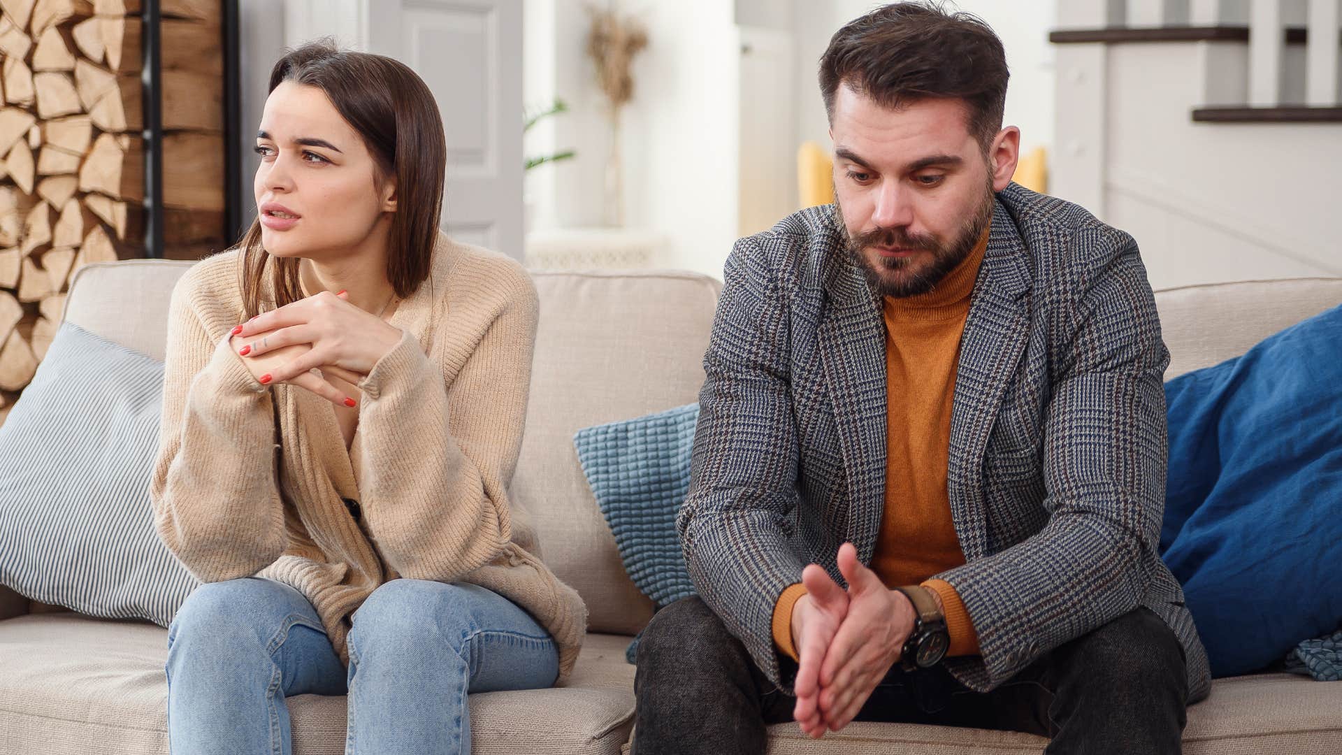 Upset couple sitting next to each other on a couch.