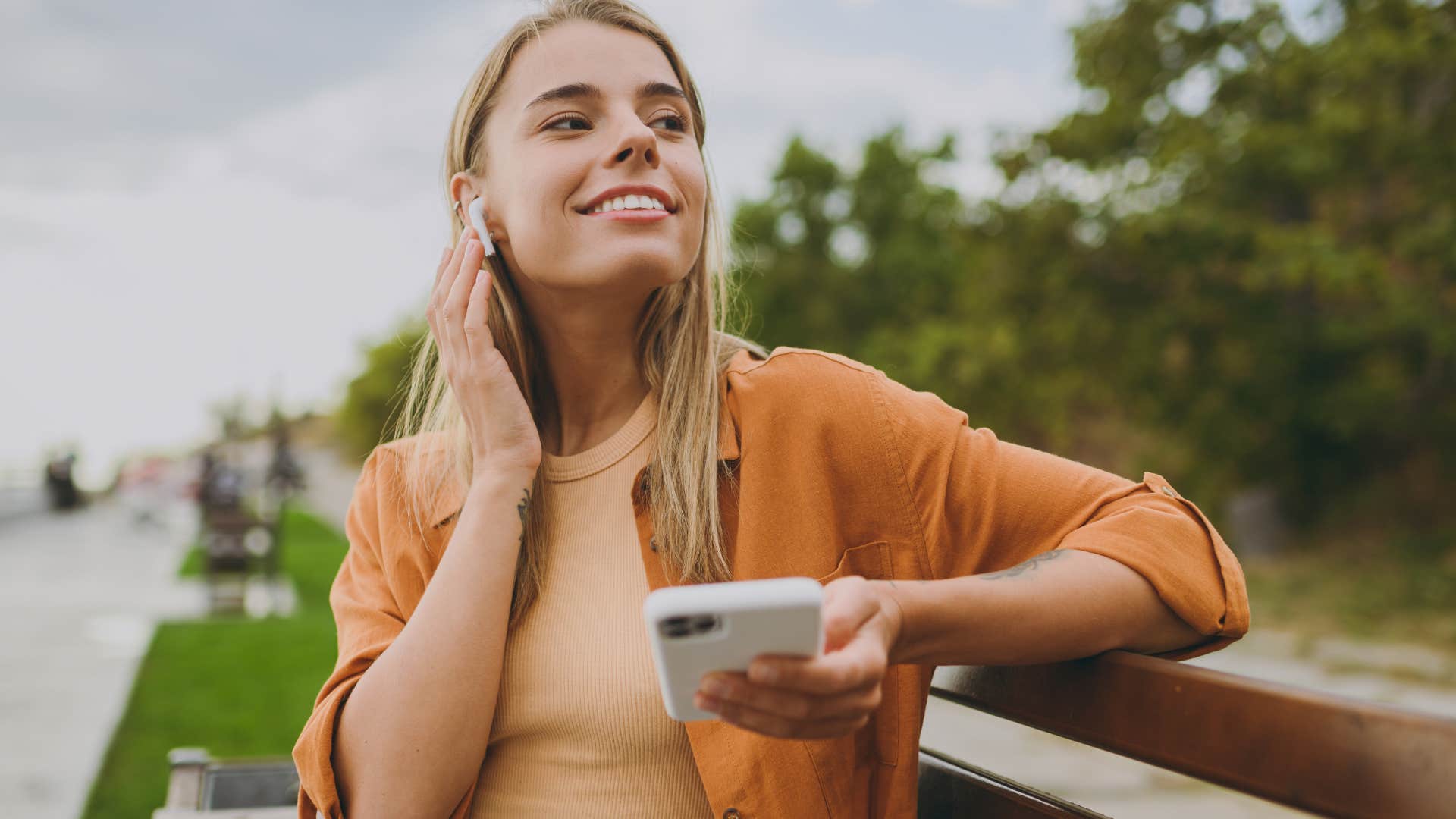 Woman smiling and listening to music with earbuds.