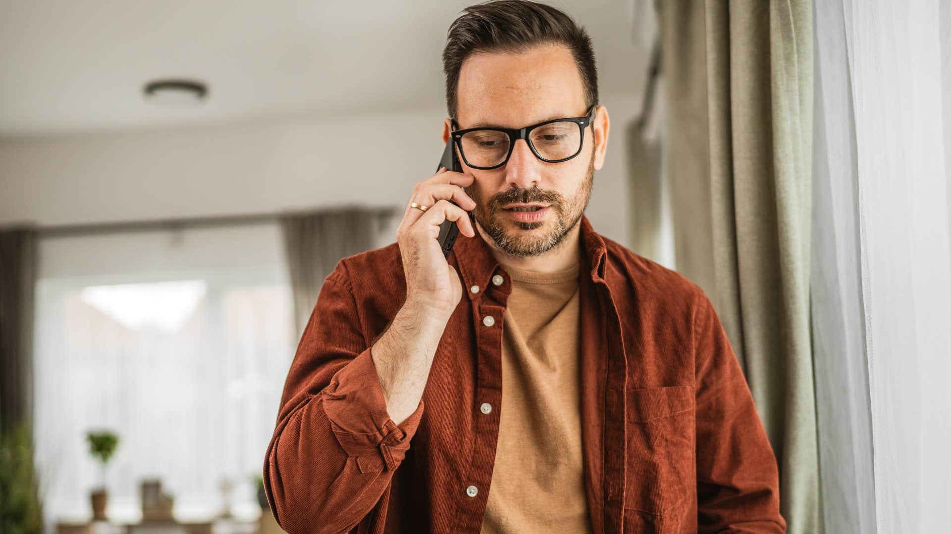 Man looking anxious talking on the phone at home.