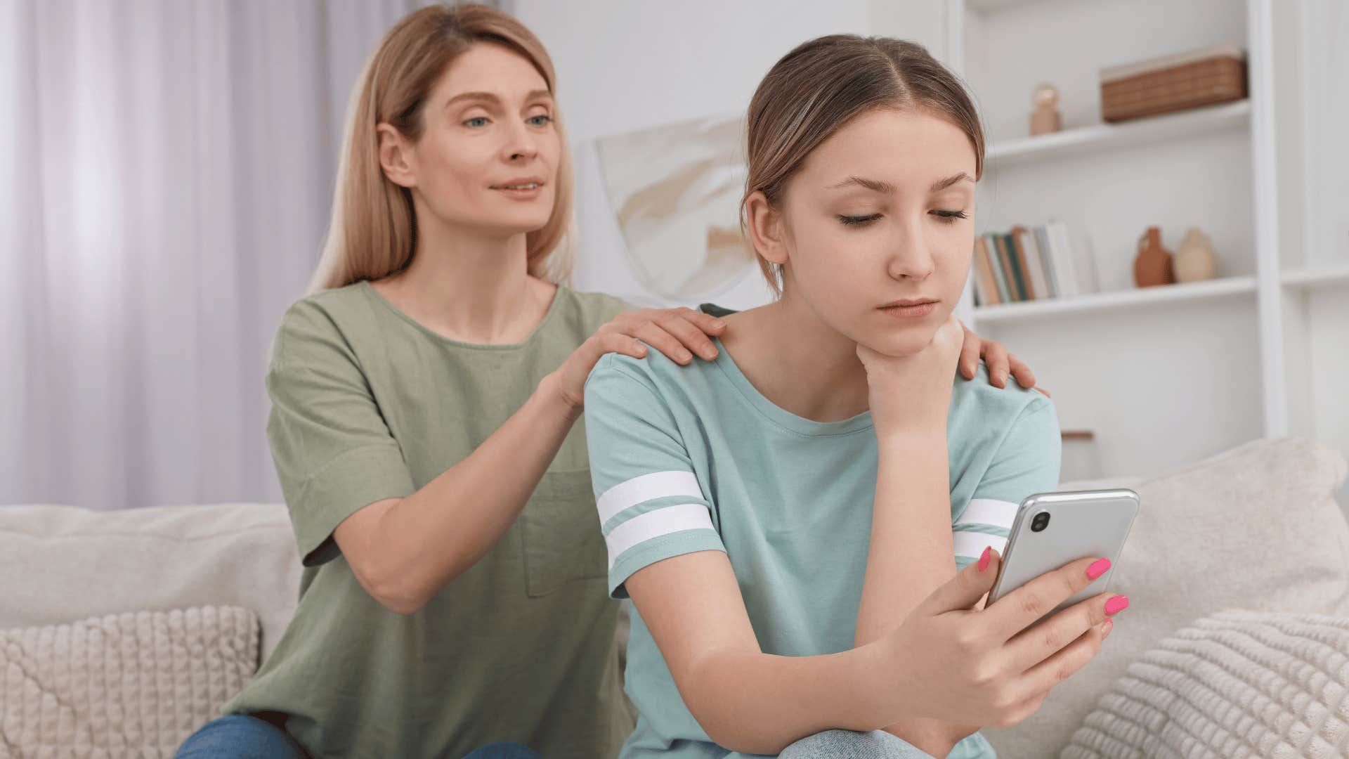 mom looking over daughter's shoulder and looking at her phone