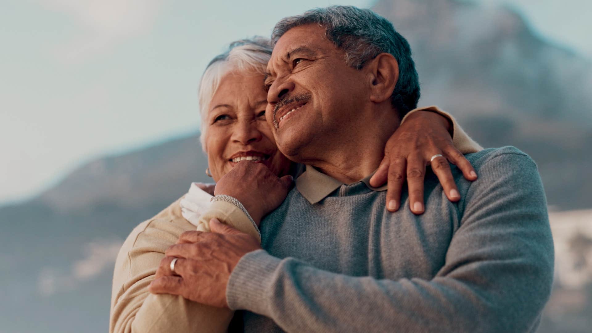 Woman smiling and hugging her partner outside.