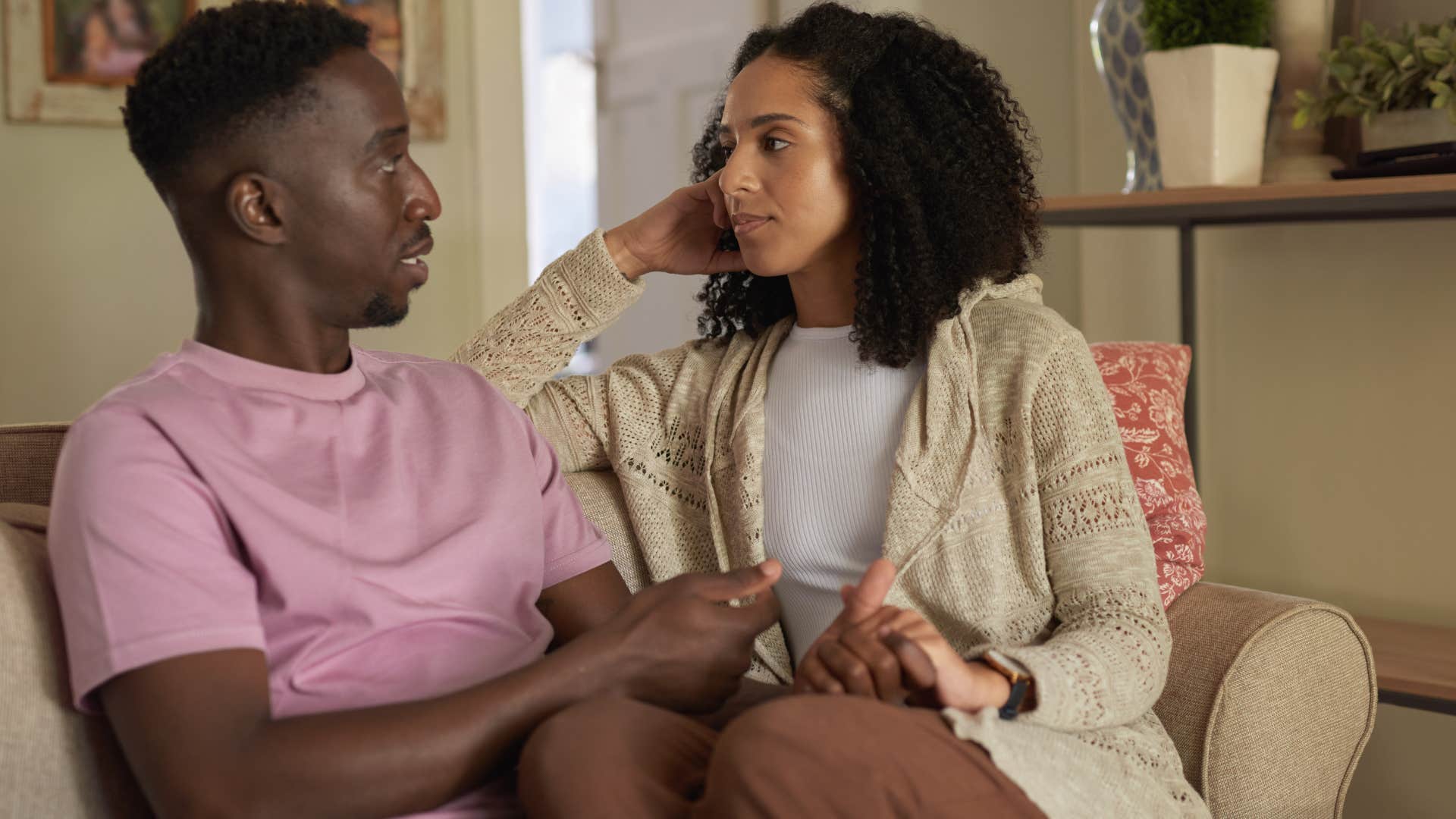 Couple having a serious conversation sitting on a couch.