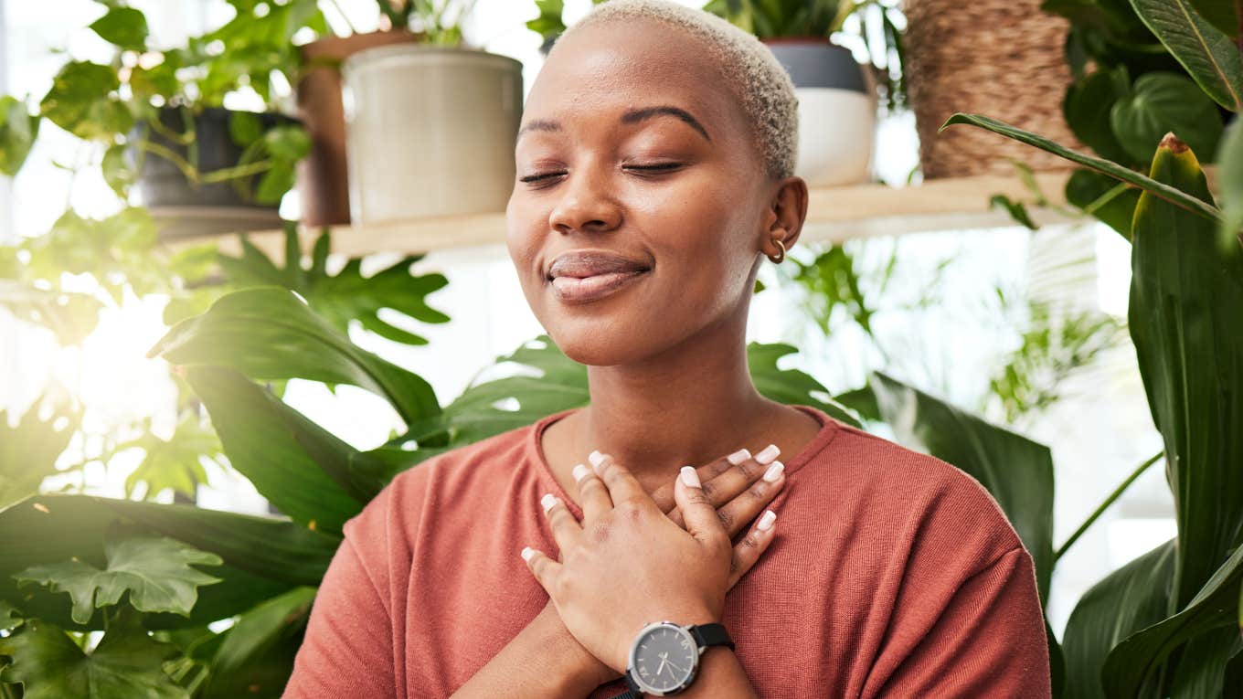 Woman smiling with her eyes closed holding her hands to her chest.