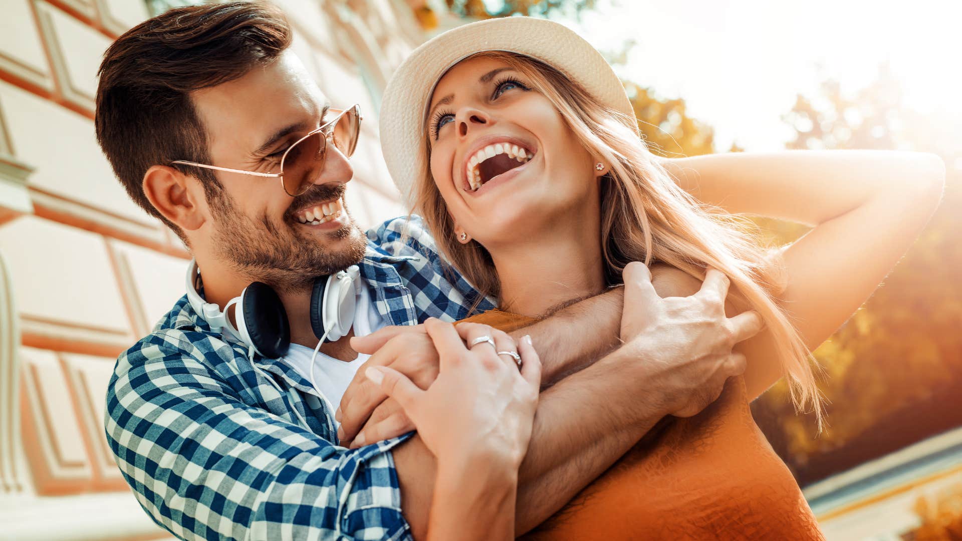 Couple smiling and hugging outside.