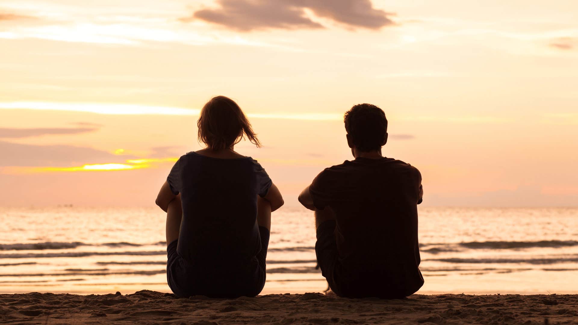 people sitting on a beach watching the water