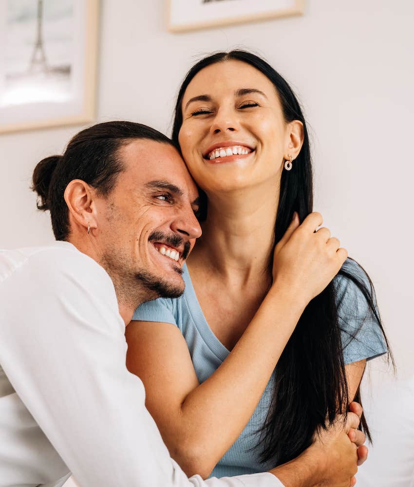 Mischievous man snuggles happy woman