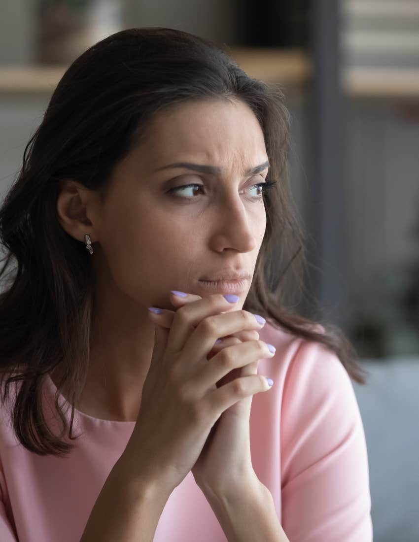 A woman with a worried expression, her brow furrowed as she appears deep in thought