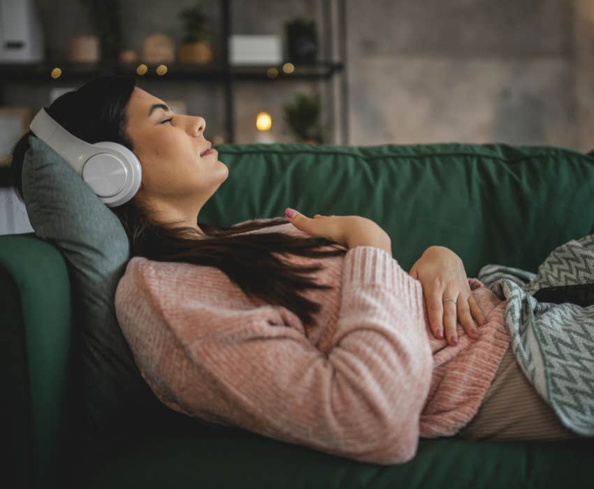 woman using headphones for online guided sound therapy meditation with eyes closed at home 