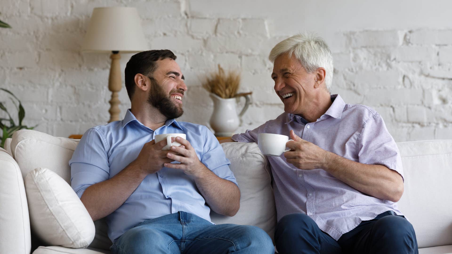 two men having conversation and laughing on couch