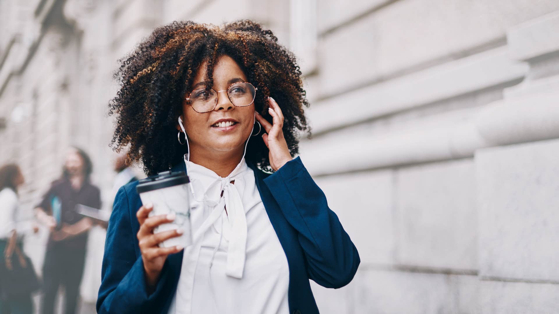 woman walking down street listening with earbuds in