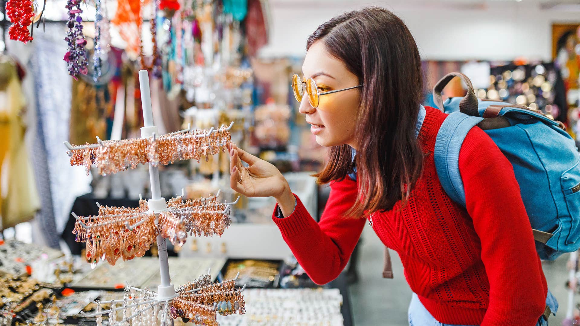 Trendy hipster woman looking for fancy jewelry and accessories in a flea market shop