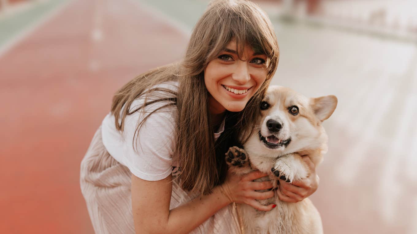 Smiling woman hugging her dog outside.