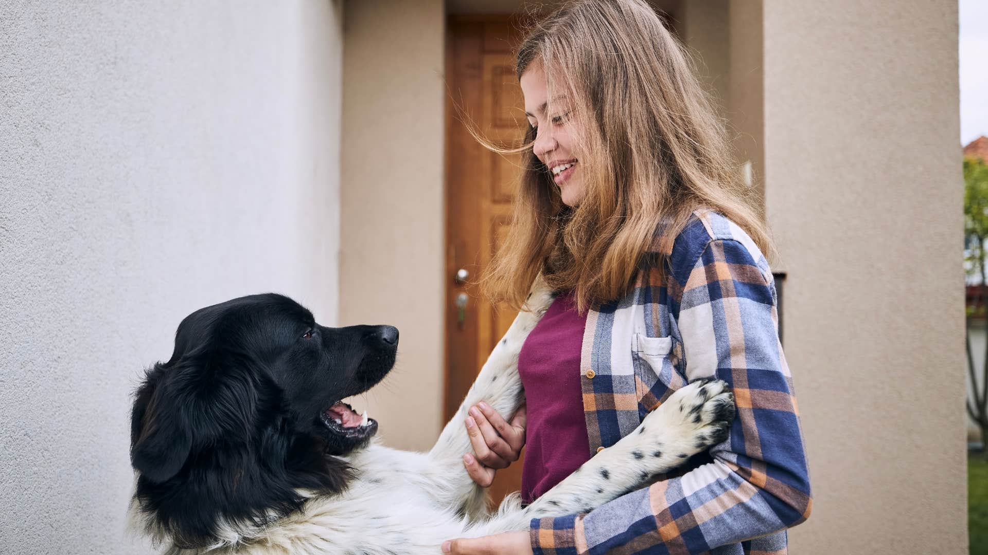 Woman smiling while her dog jumps on her