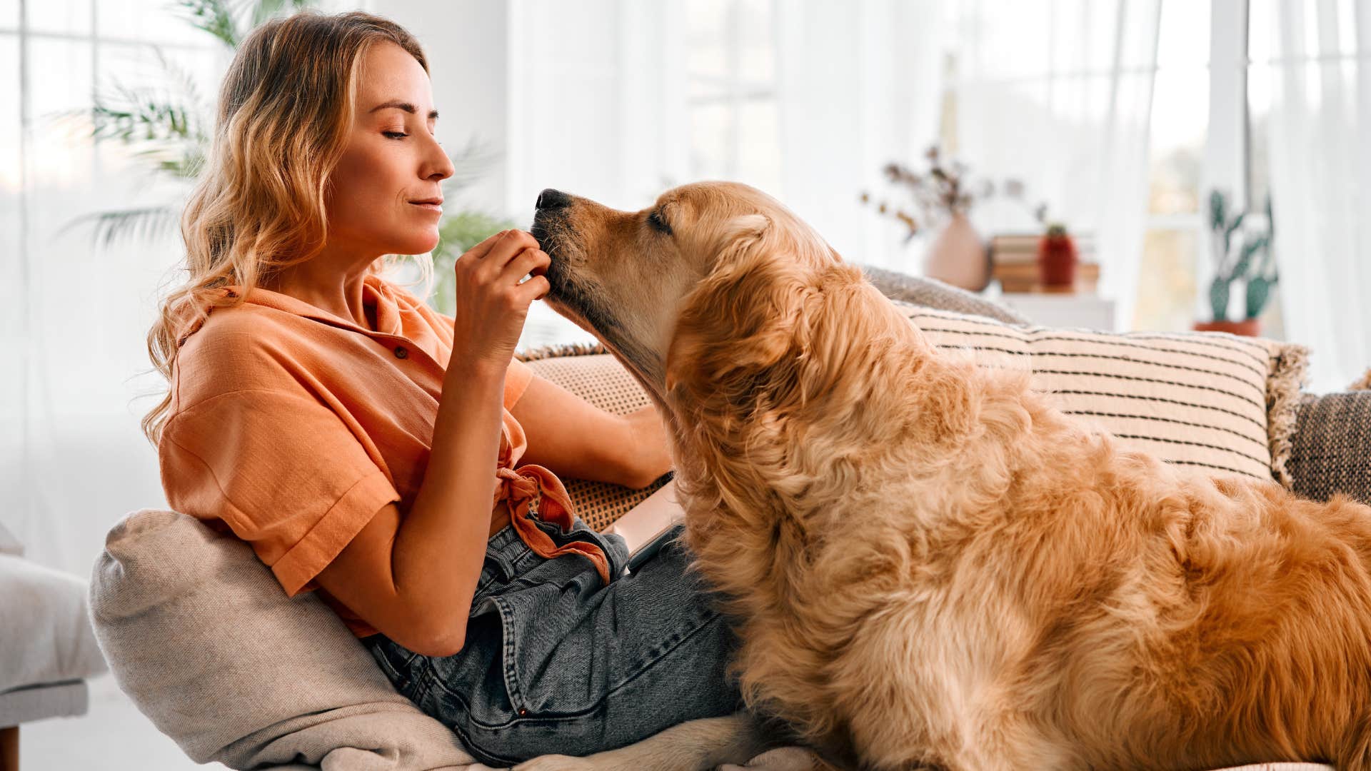 Woman smiling while her dog brings her a toy