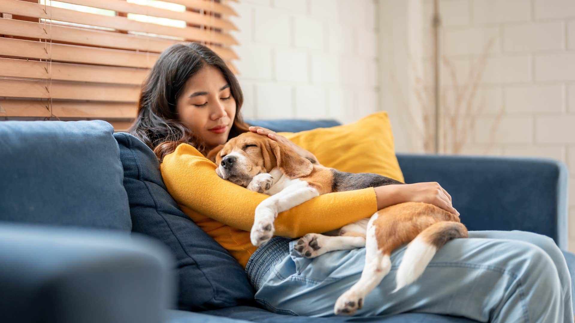 Woman smiling with a sleeping dog on her chest