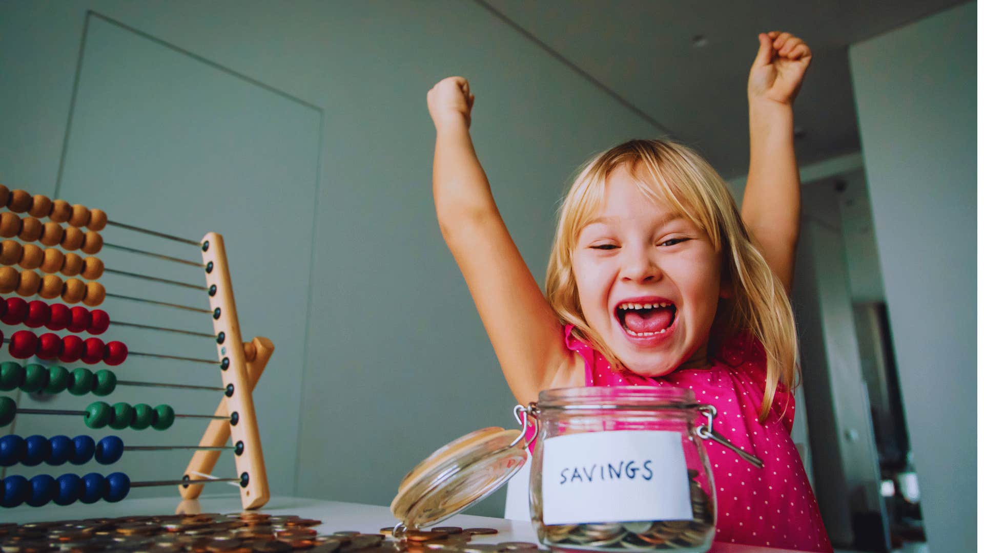 girl putting money from allowance into savings jar