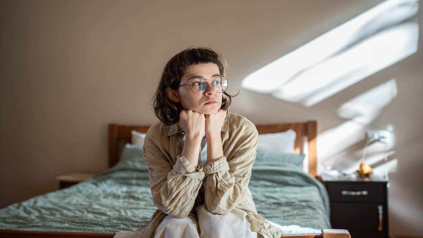 chronically single woman sitting on edge of bed by herself