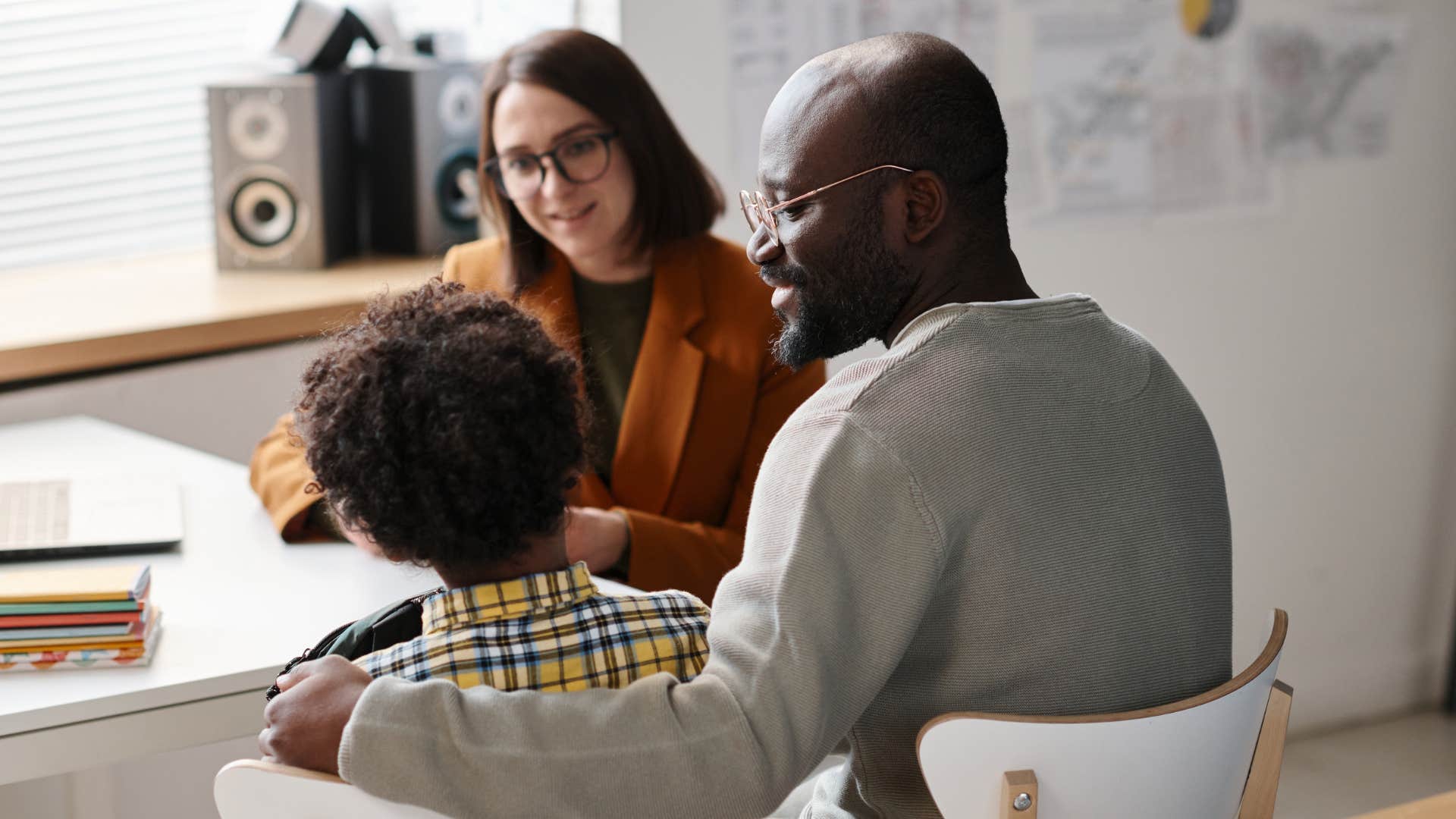 man sitting with his young child at a parent-teacher conference