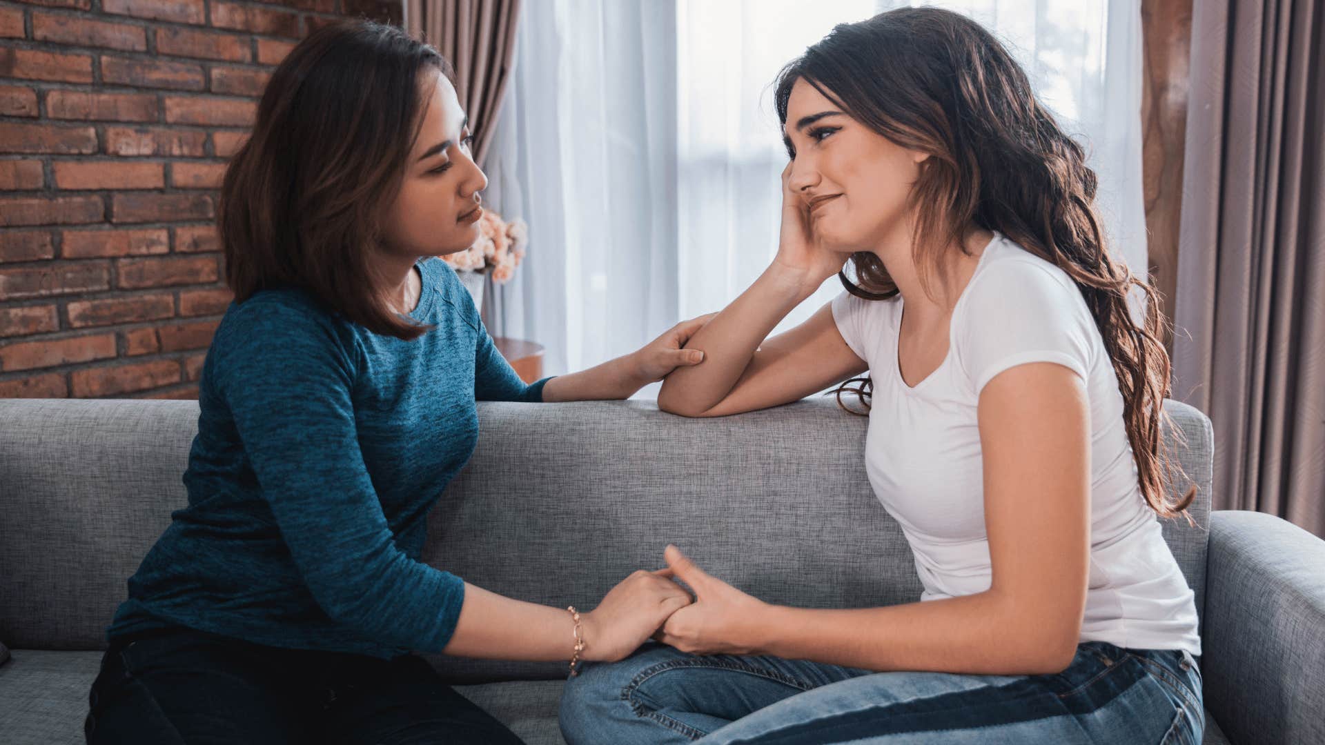 woman comforting other woman while holding her hand 