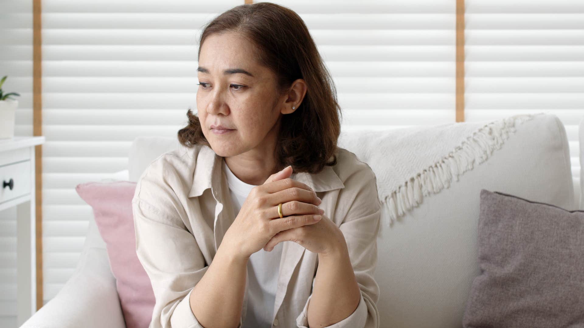 Older woman looking nervous sitting on a couch.